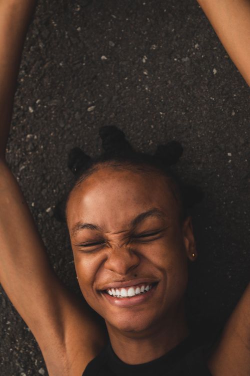 Free Close-up of a joyful woman lying on the floor with eyes closed and a bright smile. Stock Photo
