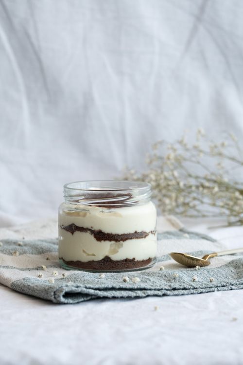 Free Delicious tiramisu dessert elegantly served in a glass jar on a rustic table setting. Stock Photo