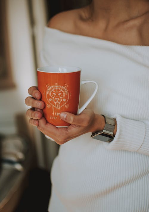 Femme Tenant Une Tasse En Céramique Blanche Et Orange