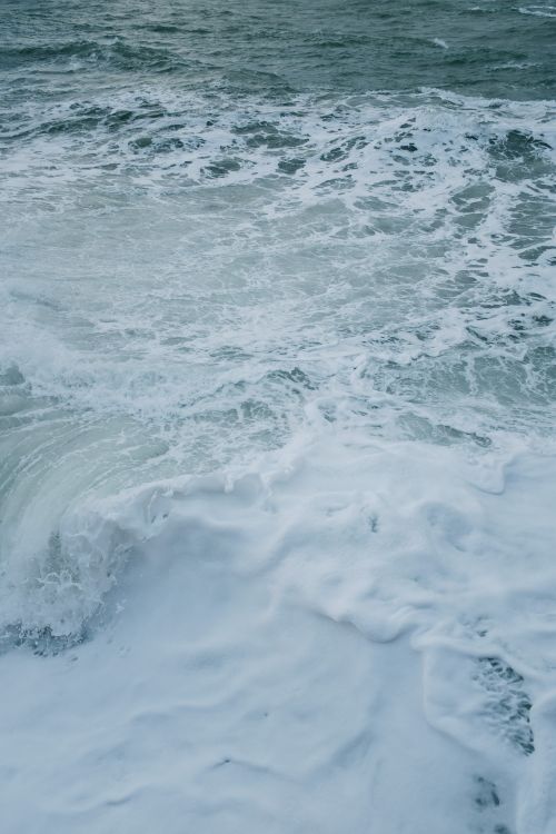 Free Captivating aerial view of waves crashing with intense foam and motion. Stock Photo