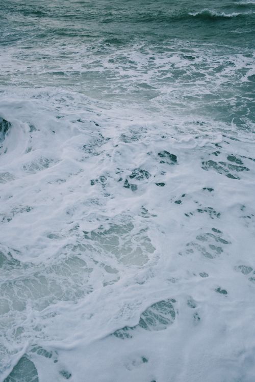 Free High angle shot of ocean waves creating foamy patterns on the water's surface. Stock Photo