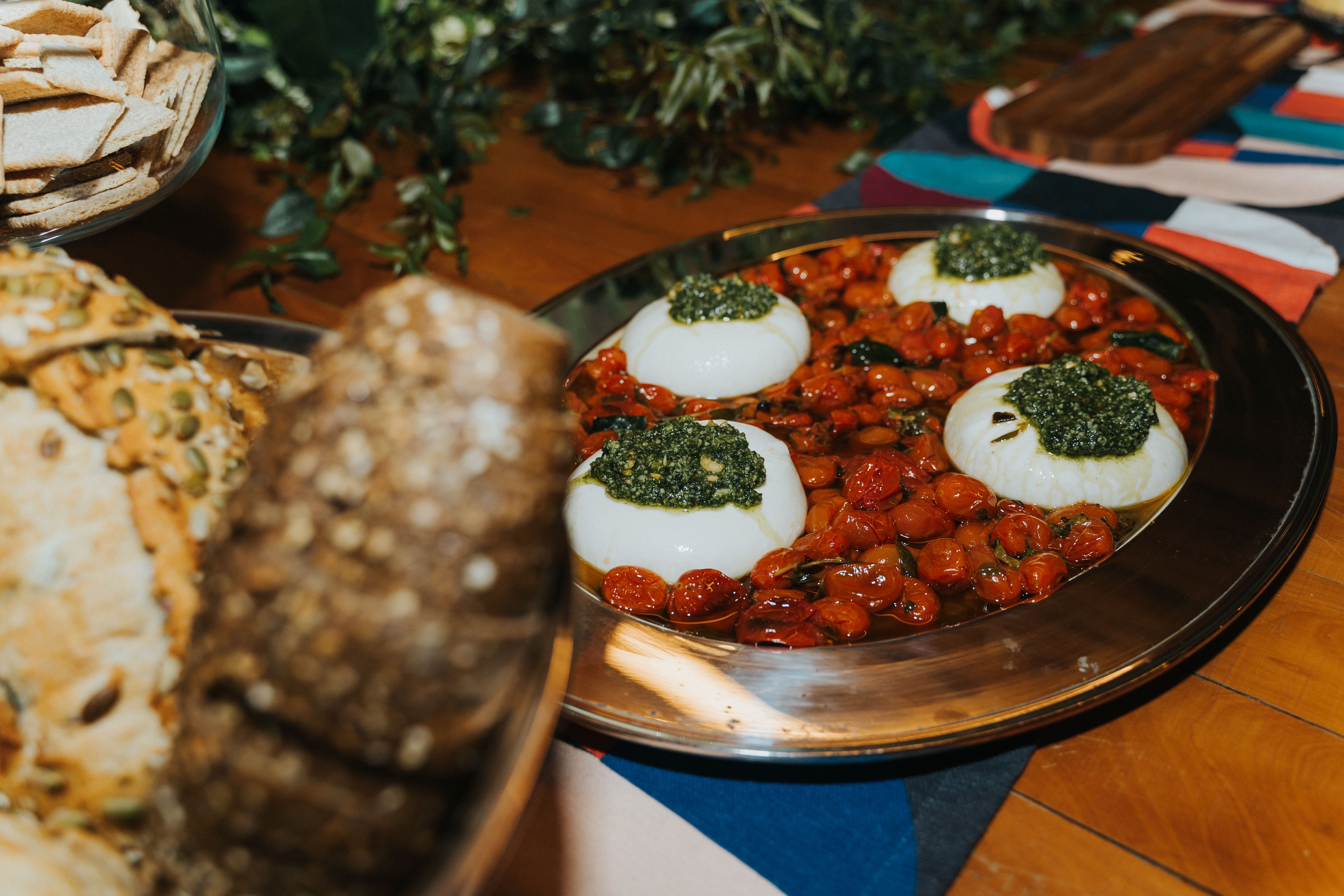 Appetizing platter with cheese, cherry tomatoes, and pesto, perfect for a gourmet meal.