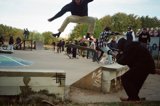 捕捉滑板运动员在空中表演技巧时，与滑板公园旁观者互动的精彩瞬间