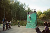 在城市滑板公园的坡道上，滑板运动员表演着大胆的技巧，引来人群围观