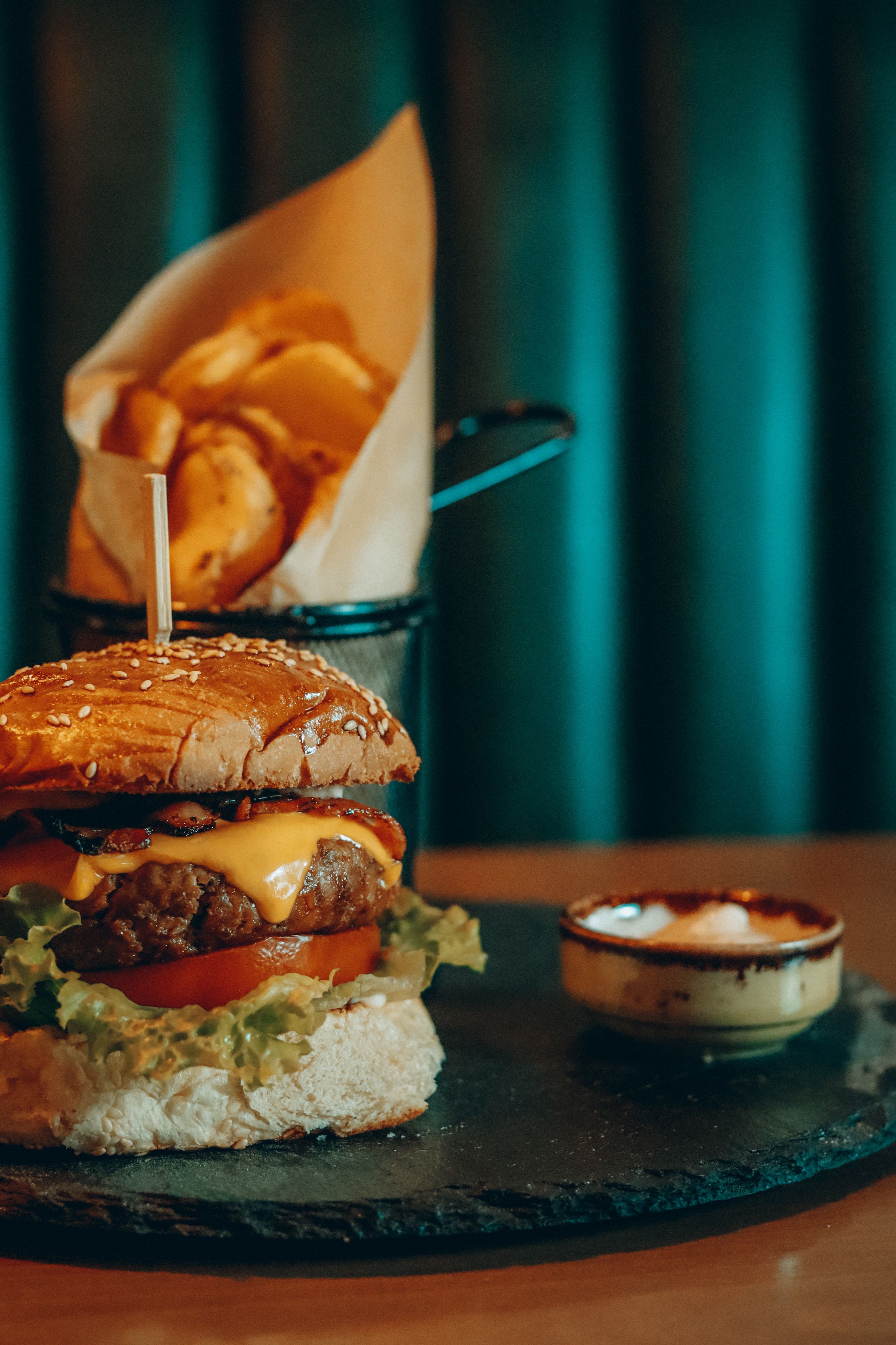 Mouthwatering cheeseburger with fries on a black plate, perfect for food lovers.