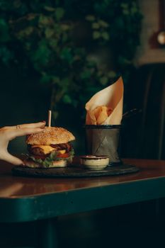 Gourmet burger with cheese and fries in a stylish restaurant setting, perfect for food lovers.