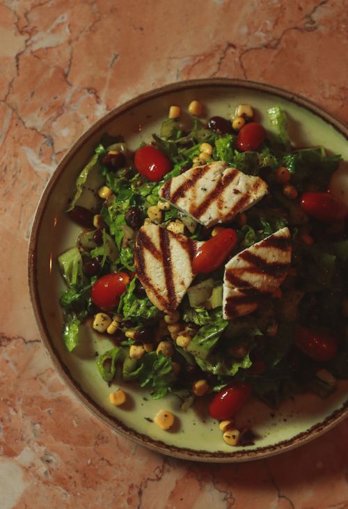 Free A vibrant top view of a grilled chicken salad with mixed greens and cherry tomatoes. Stock Photo