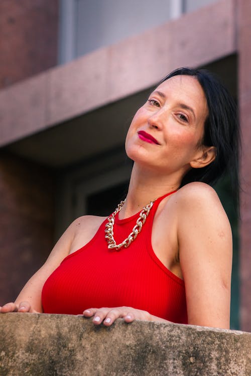 Close-Up Shot of a Woman in Red Sleeveless Shirt Wearing Her Chain Necklace
