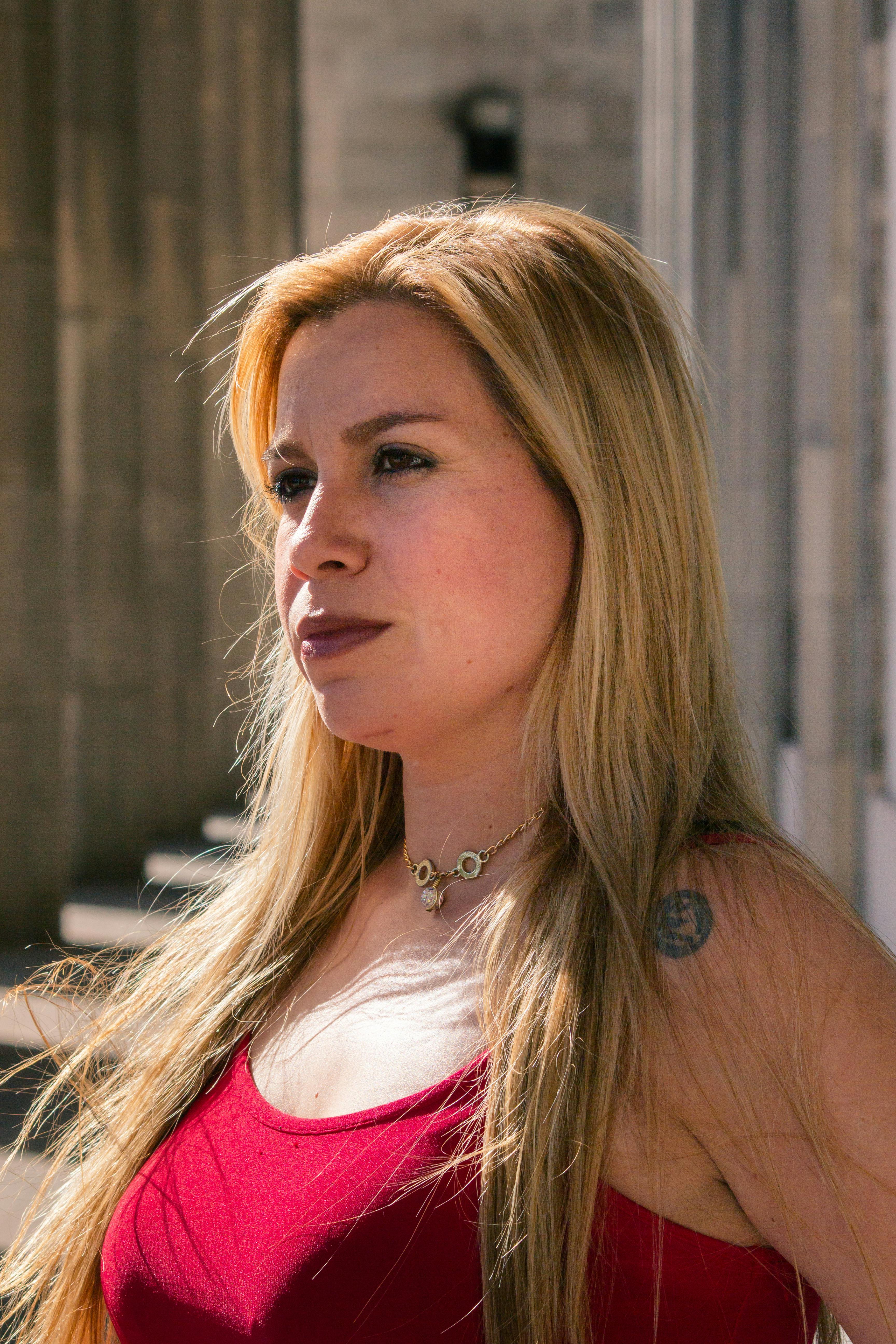 A confident woman with blond hair stands outdoors under sunlight in Buenos Aires.