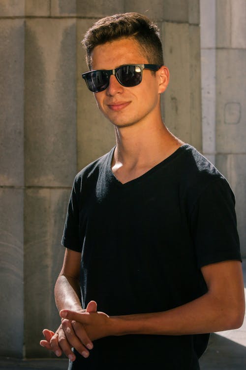 handsome young man wearing sunglasses sitting with bottles of red