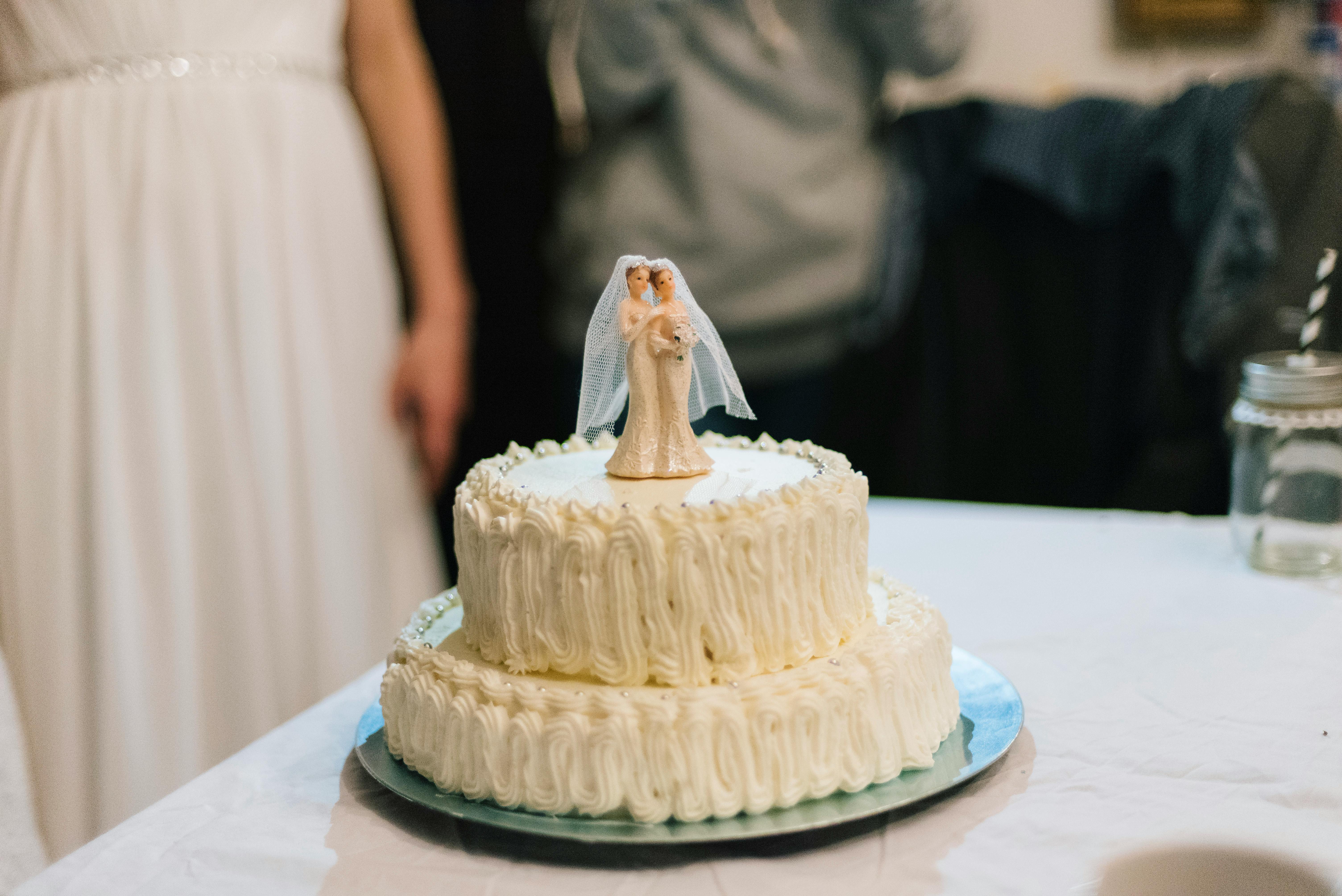 Close-up of a white wedding cake with a bride and groom topper, perfect for wedding celebrations.