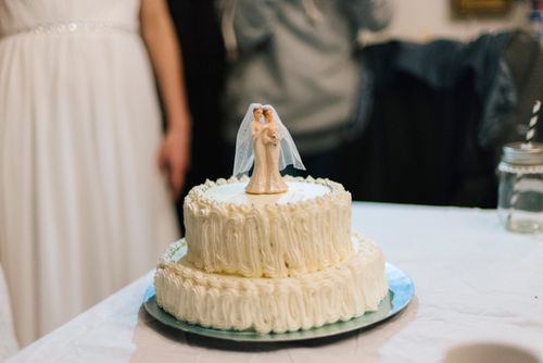 Free Close-up of a white wedding cake with a bride and groom topper, perfect for wedding celebrations. Stock Photo