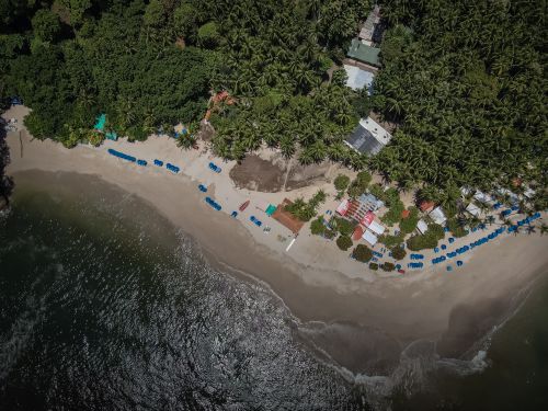 Free Drone shot of a picturesque beach in Paquera, Costa Rica, surrounded by lush palms. Stock Photo