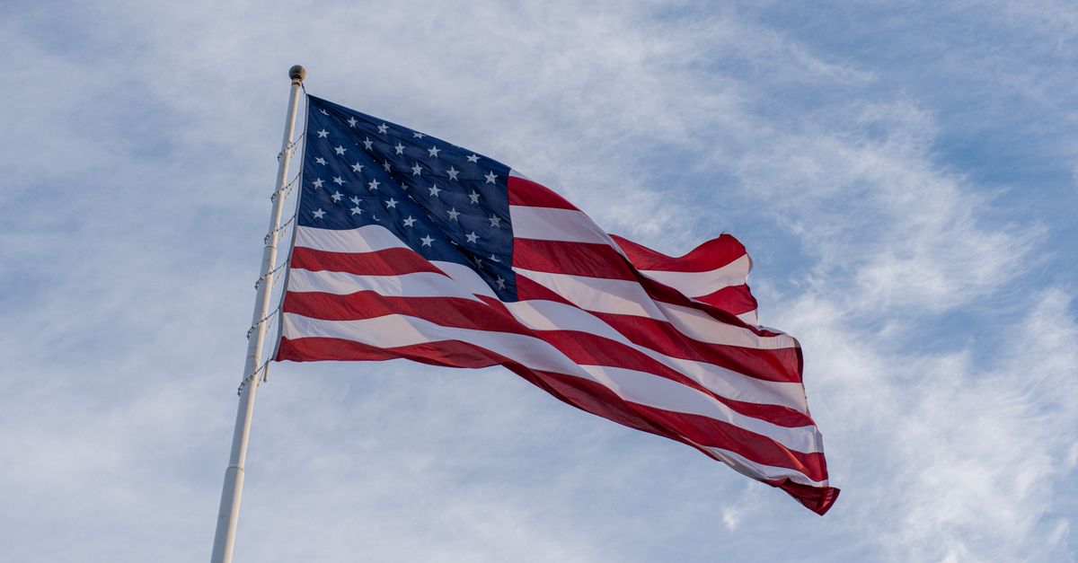 American flag waving proudly against a clear blue sky, symbolizing freedom and patriotism.