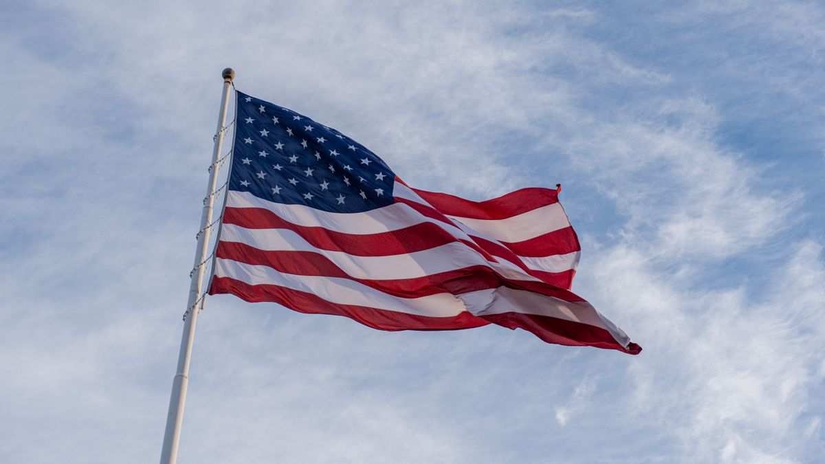 The American flag waves proudly against a backdrop of blue sky, symbolizing freedom and patriotism.