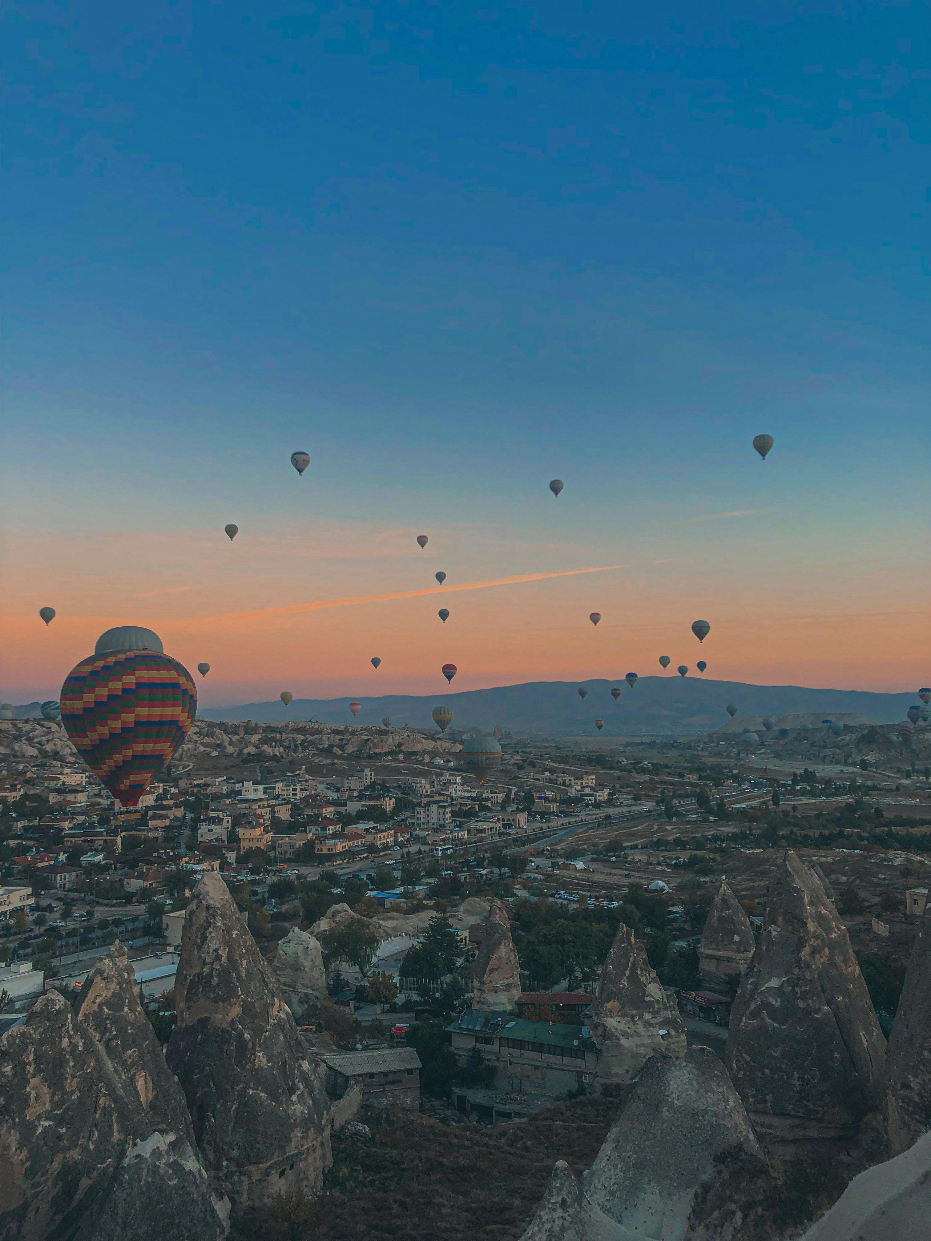 Stunning view of hot air balloons at sunrise over the rock formations in Cappadocia, Turkey.