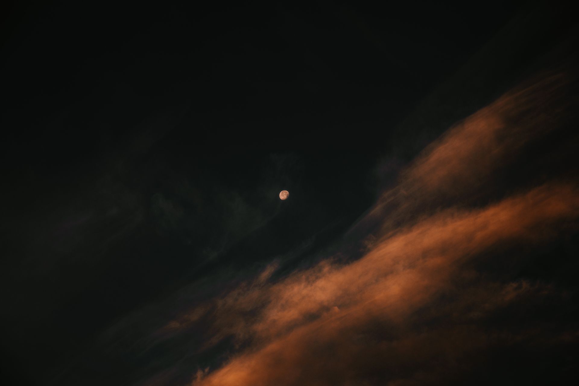 A beautiful full moon surrounded by dark clouds in a night sky, creating a mysterious atmosphere.