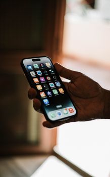 Close-up of a hand holding a smartphone with apps on the screen in focus.