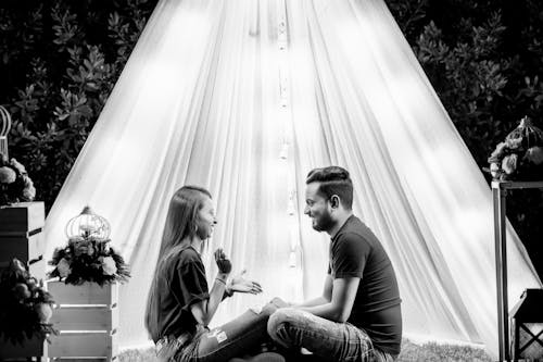 Grayscale Photo of a Couple Smiling while Sitting