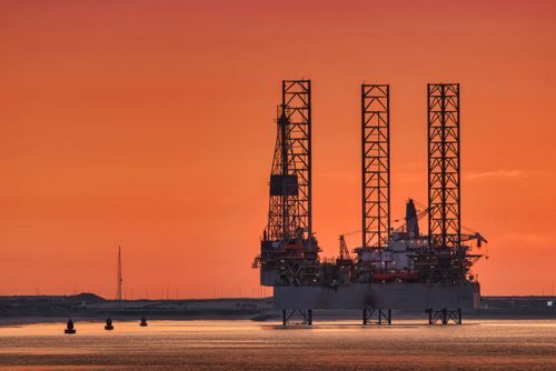 Free A striking view of an oil rig silhouetted against a fiery sunset in Rotterdam harbor. Stock Photo