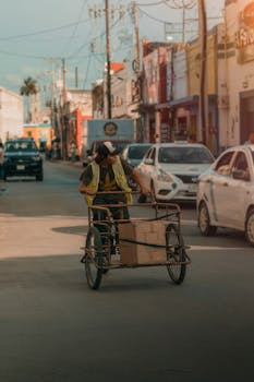 A delivery cyclist maneuvers through a busy town street, wearing a reflective vest.