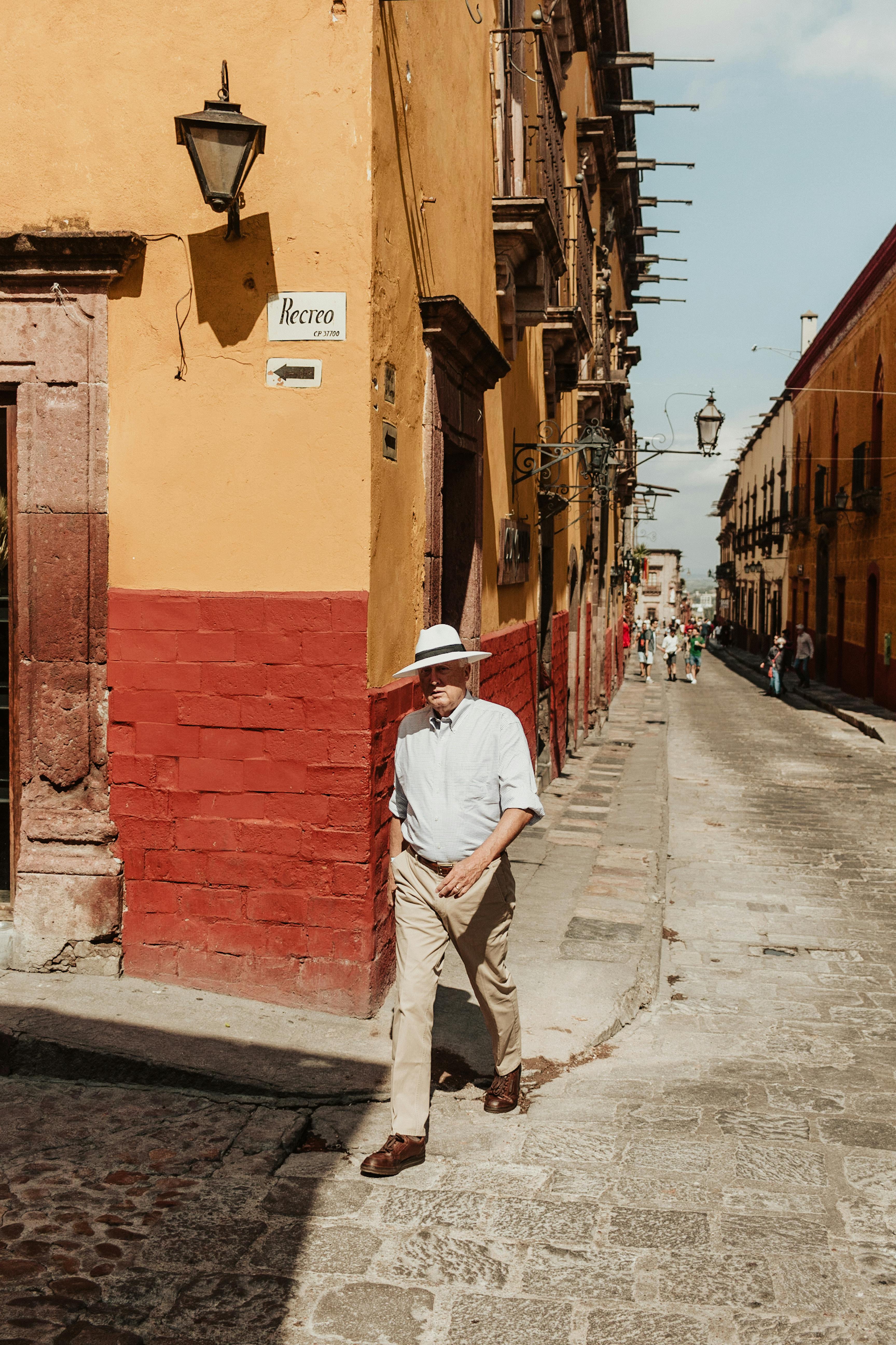 Man walking on a charming street in San Miguel de Allende, Mexico, showcasing colorful architecture.