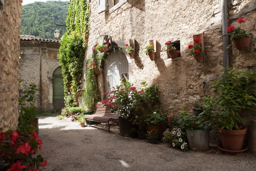 Free Picturesque alley in Die, France, adorned with vibrant flowers and rustic stone walls. Stock Photo