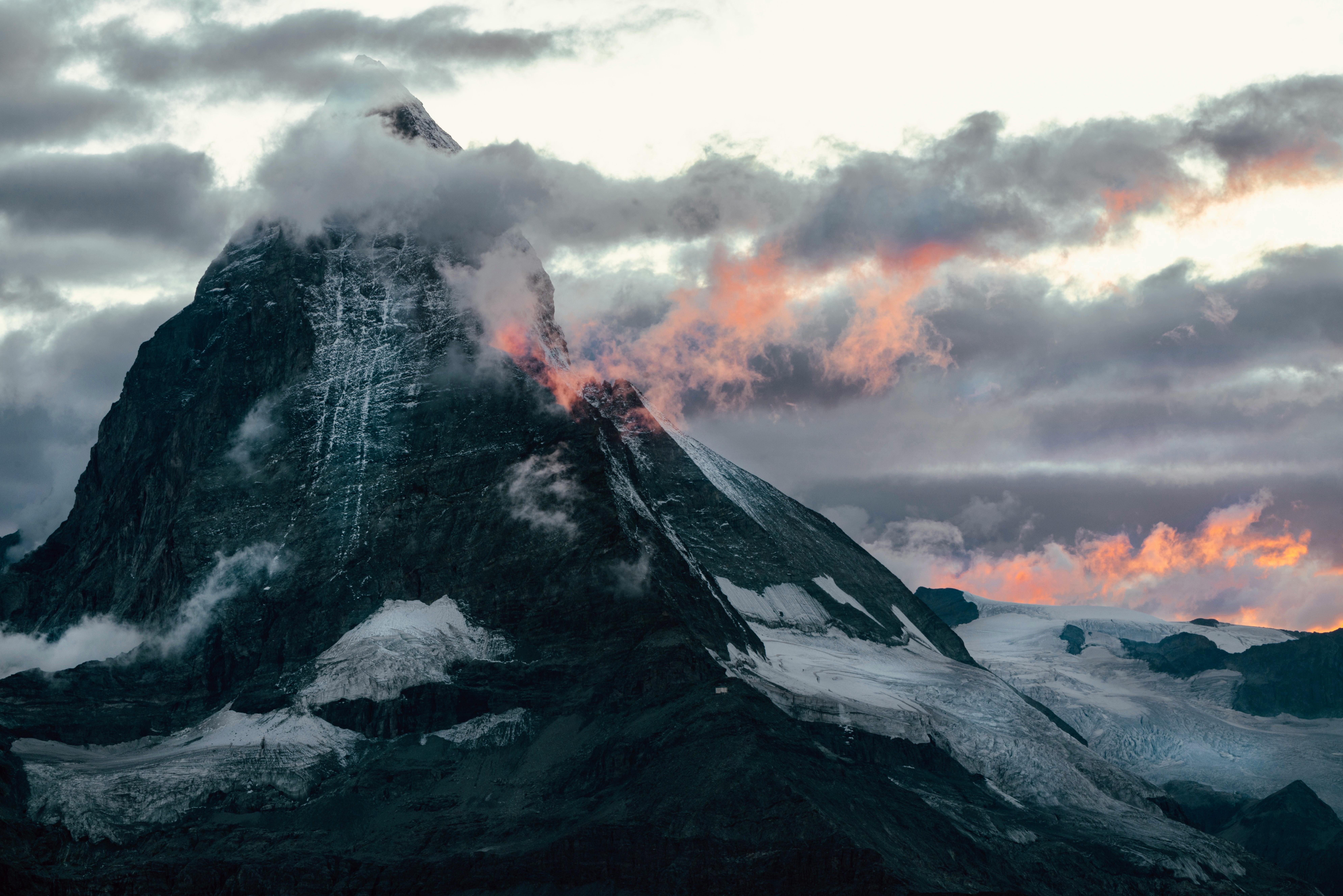 Stunning view of the Matterhorn with dramatic clouds and sunset glow in Switzerland's Alps.