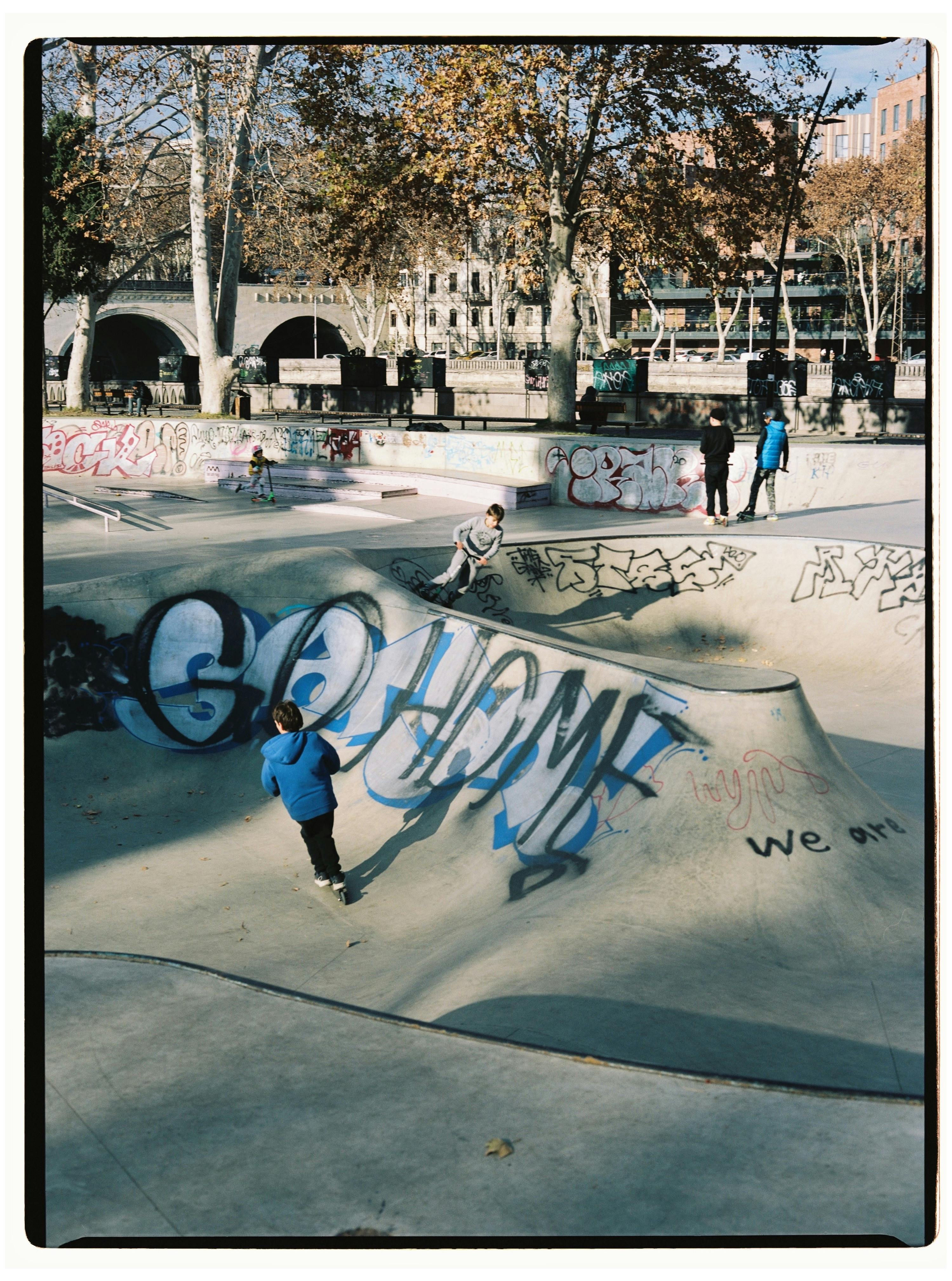 Boys enjoying skateboarding at a graffiti-covered skate park in Tbilisi, Georgia.