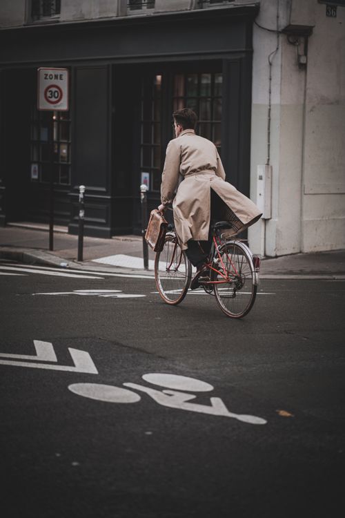 Free Man in trench coat riding bicycle on a Paris street in autumn. Stock Photo