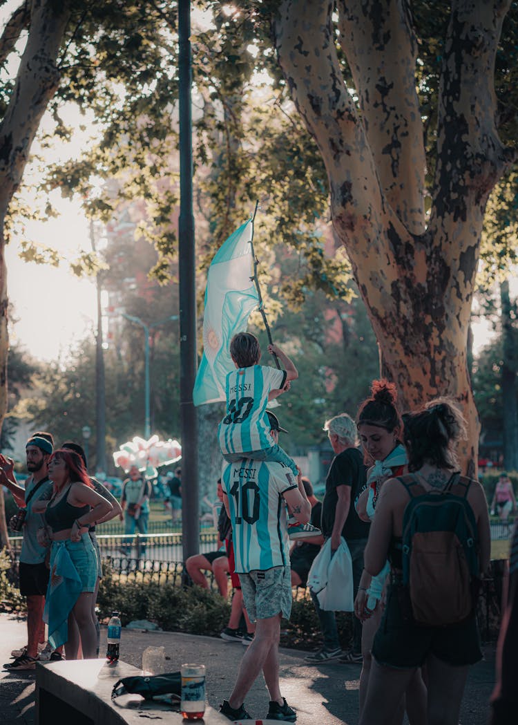 Man Carrying His Flag Waving Son On His Shoulders