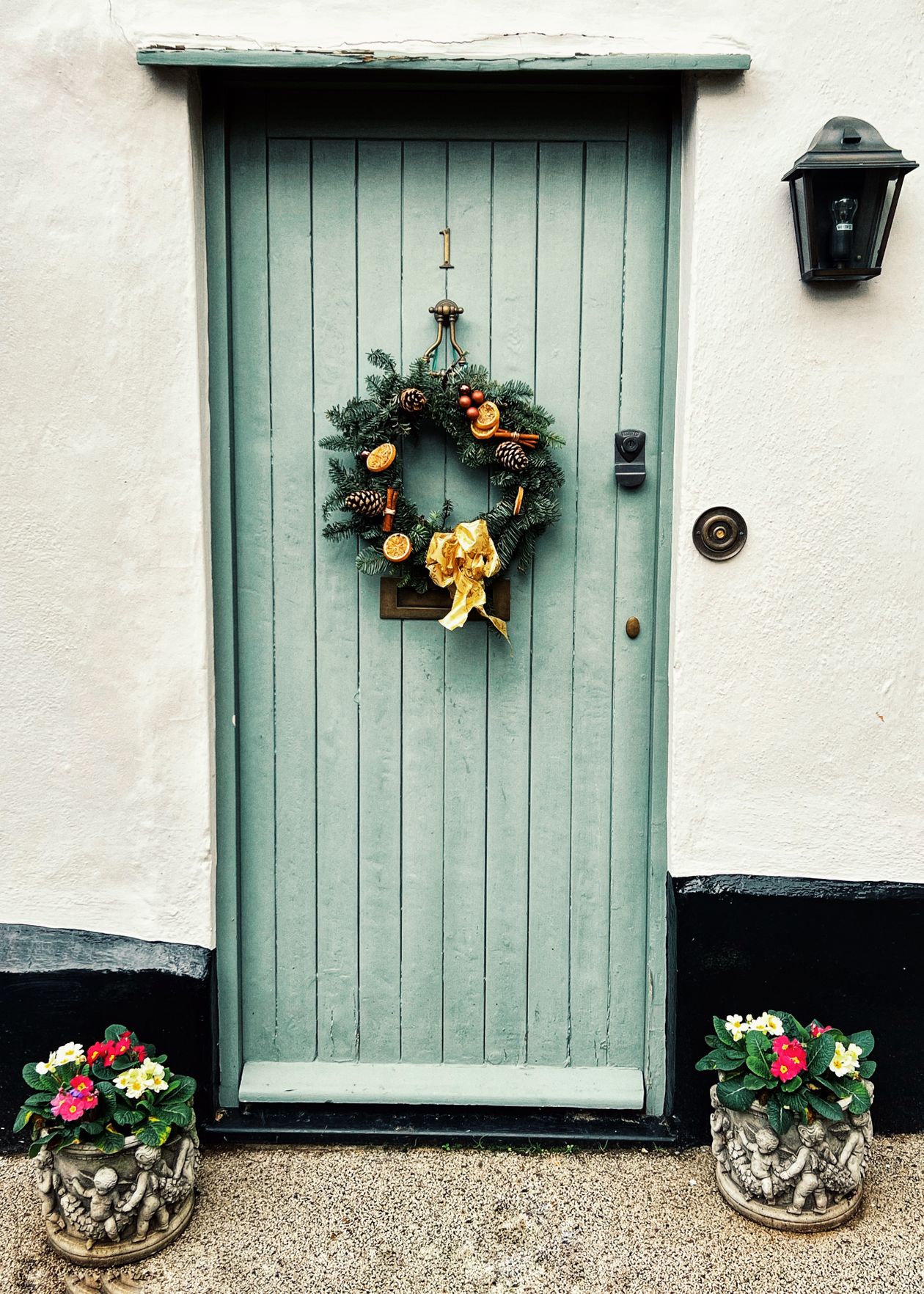 how to style a front door wreath: a green door with a floral wreath and flower pots