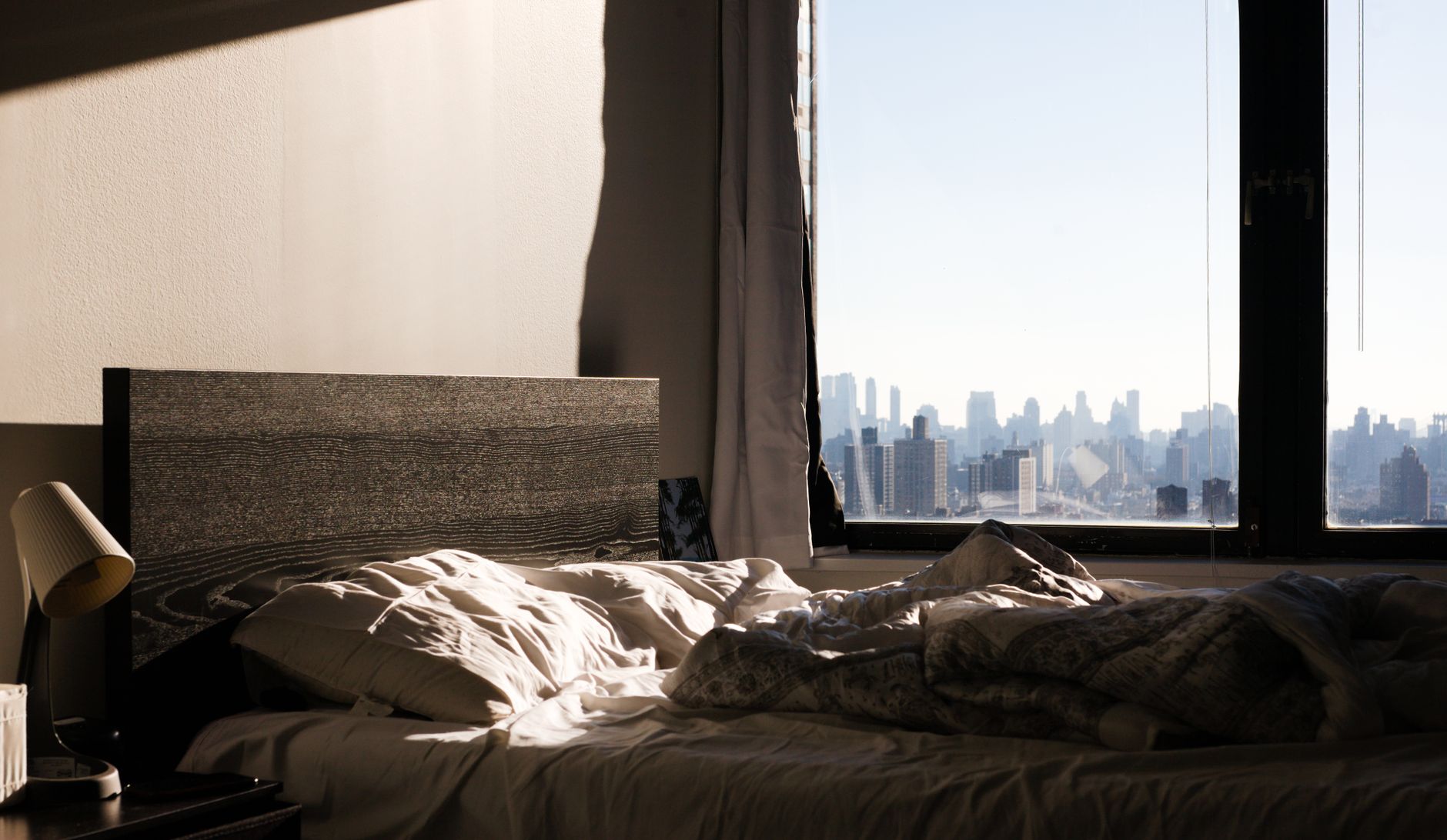 Modern bedroom with a stunning view of the New York City skyline through the window.