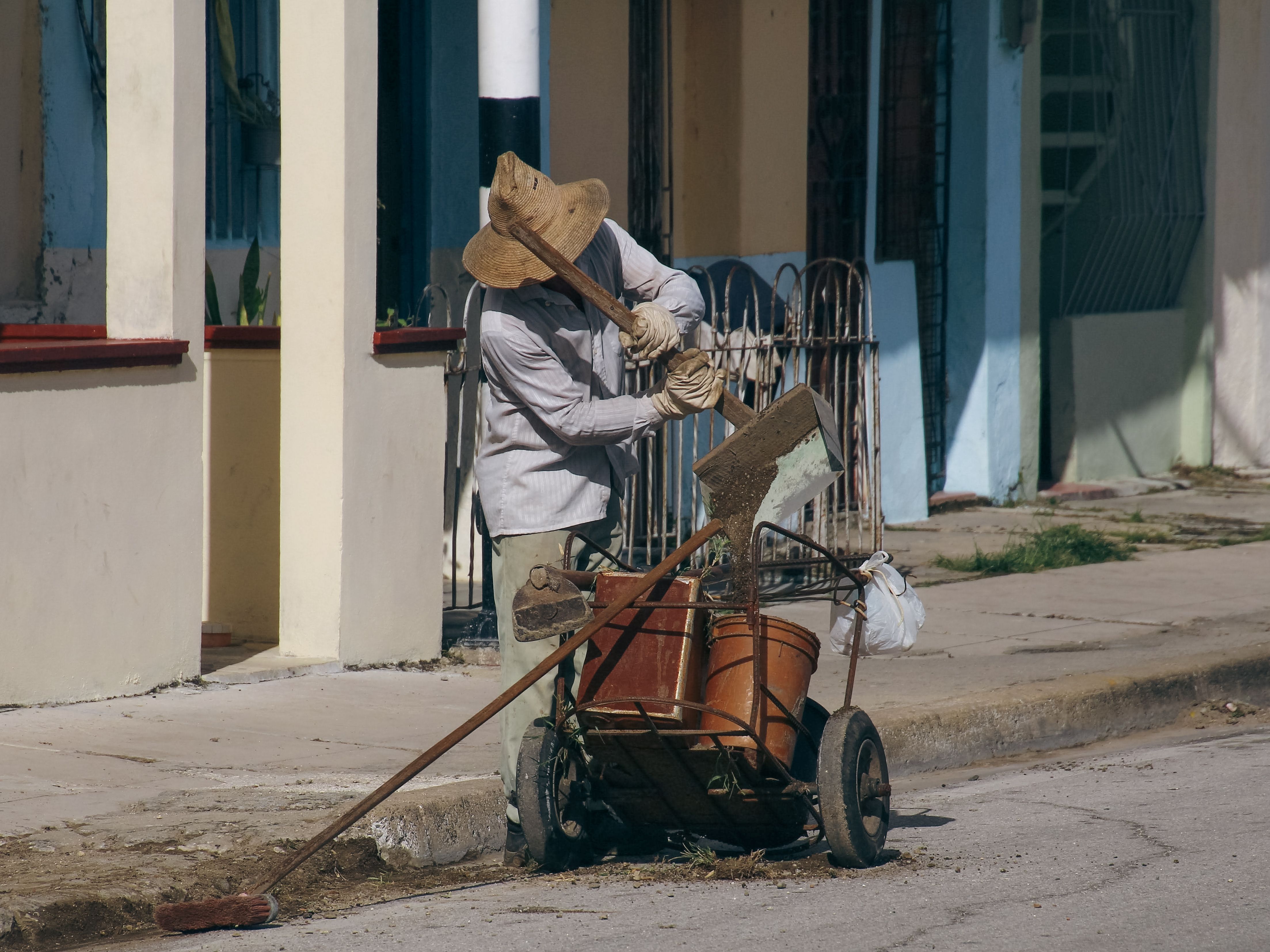 Man Sweeping Streets Throwing away Dust in Bin · Free Stock Photo