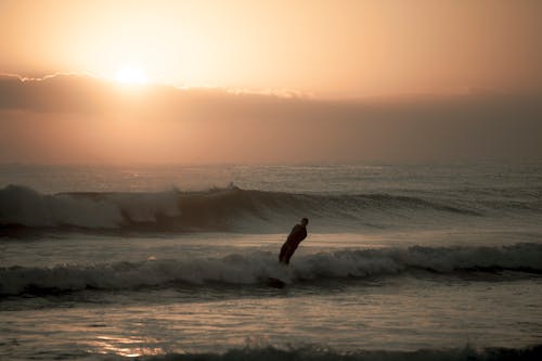 A Man Surfing during Sunset