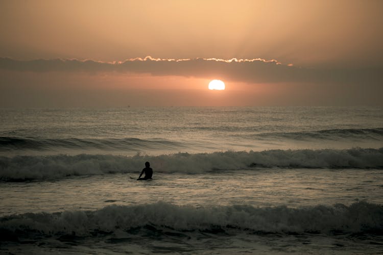 Surfer In Sea At Sunrise