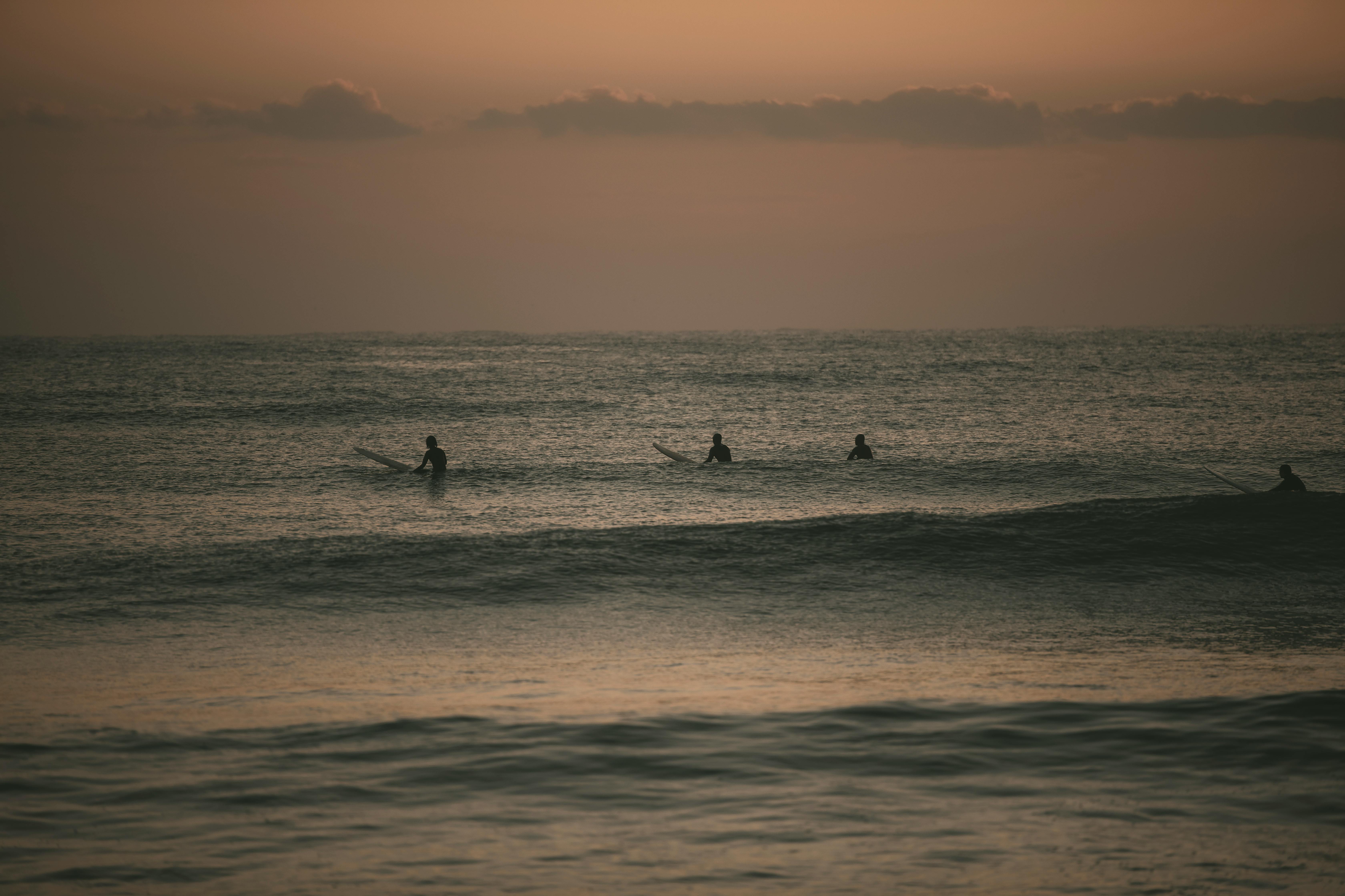 Surfers catching waves at sunset in Yangyang, South Korea. Ideal for travel and sports themes.