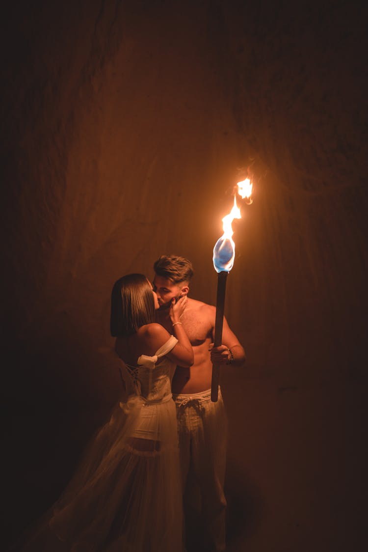 Couple Sharing A Kiss By The Torchlight