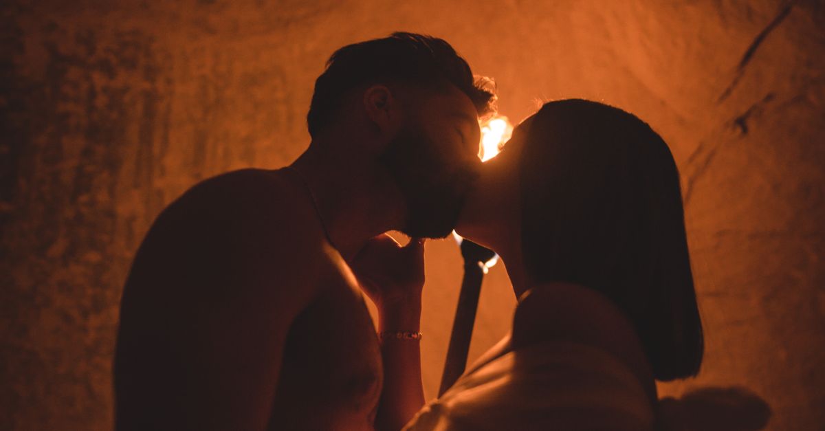 Rüyada Gizli İlişki Sürdürmek - Rüya Tabiri ve Anlamı - Silhouetted couple sharing a kiss in a dimly lit cave, illuminated by torchlight.