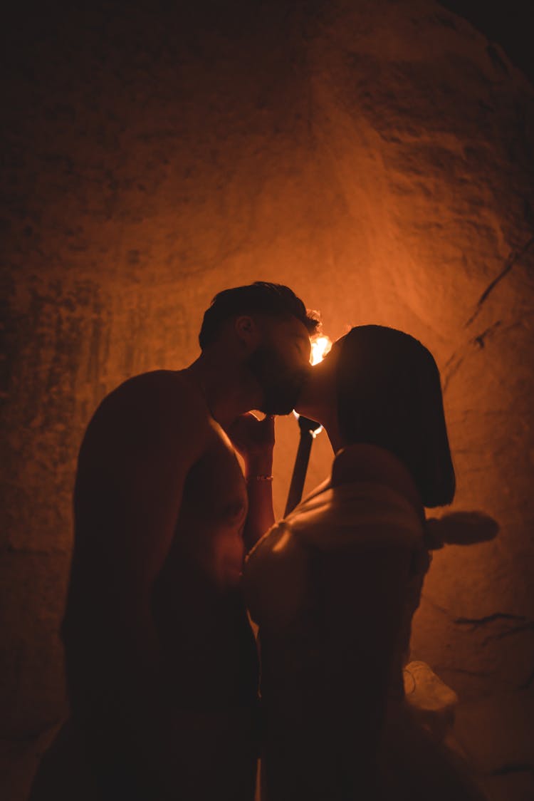 Silhouettes Of Couple Sharing A Kiss By The Torchlight