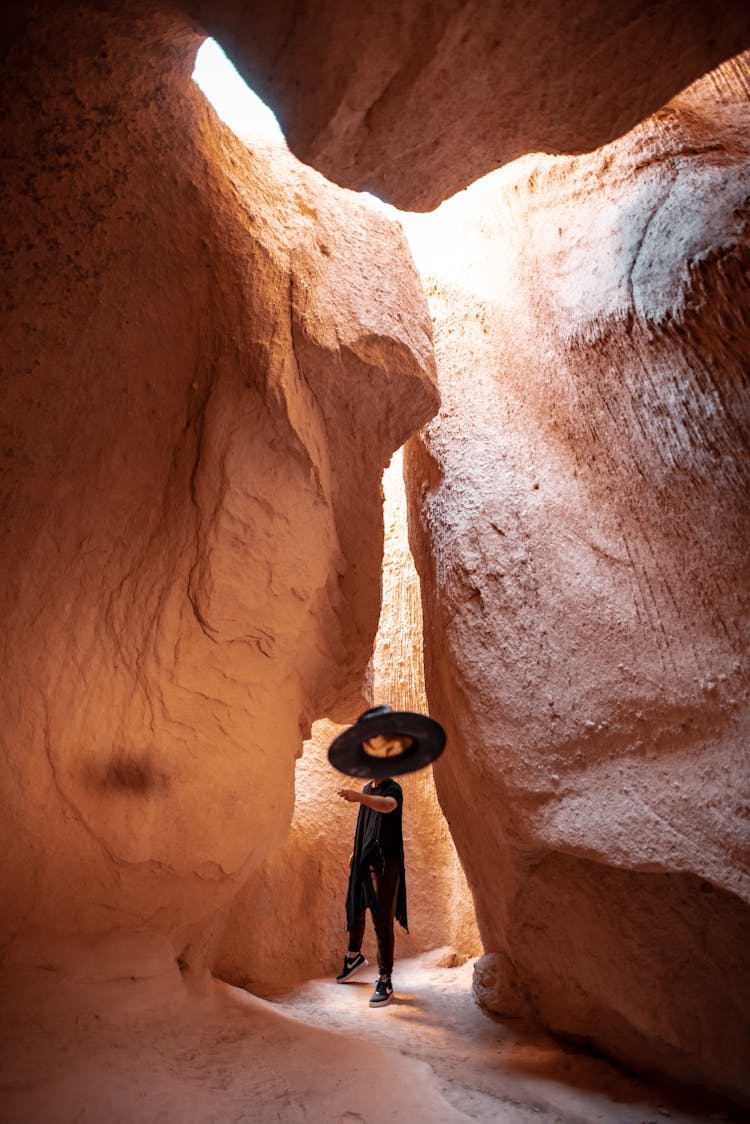 Person Standing In Cave Throwing Hat