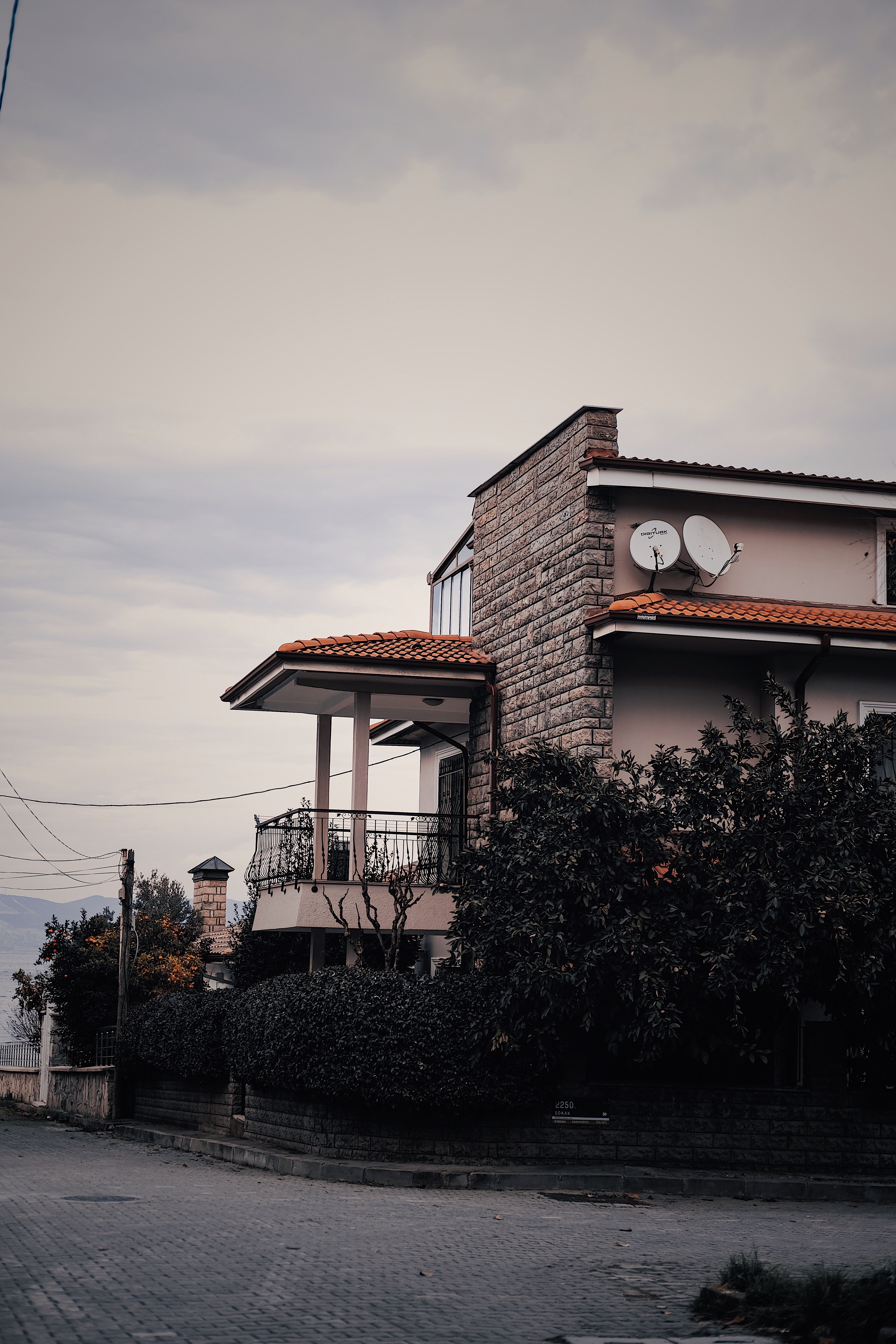 A charming house with a red roof surrounded by greenery in İzmit, Kocaeli, Turkey, under a cloudy sky.