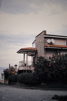 A charming house with a red roof surrounded by greenery in İzmit, Kocaeli, Turkey, under a cloudy sky.