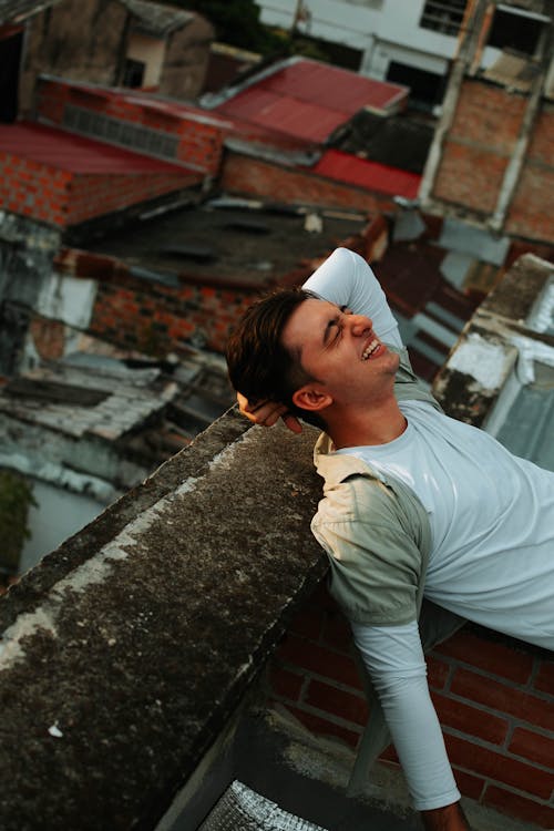 Smiling Man Lying Down on Wall on Roof