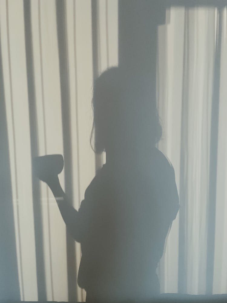 A Shadow Of A Person On A White Curtain