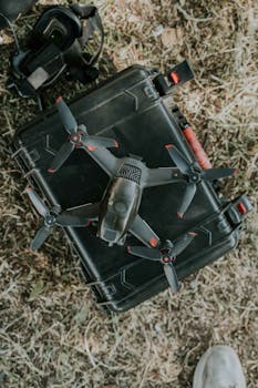 Aerial photography drone placed on a portable hard case on grass, ready for flight.