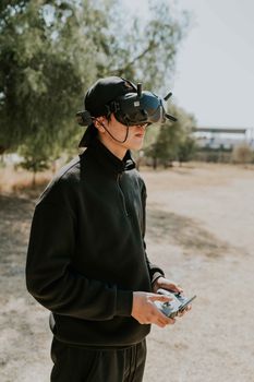 A man stands outdoors using VR goggles and a controller for an immersive virtual experience.