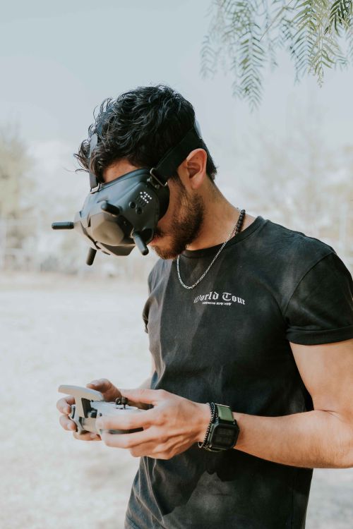 Free A man using VR goggles and a controller outdoors, showcasing modern technology. Stock Photo
