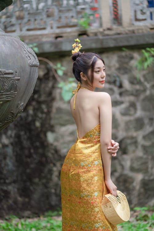 A Woman in Yellow Backless Dress Holding a Hand Bag