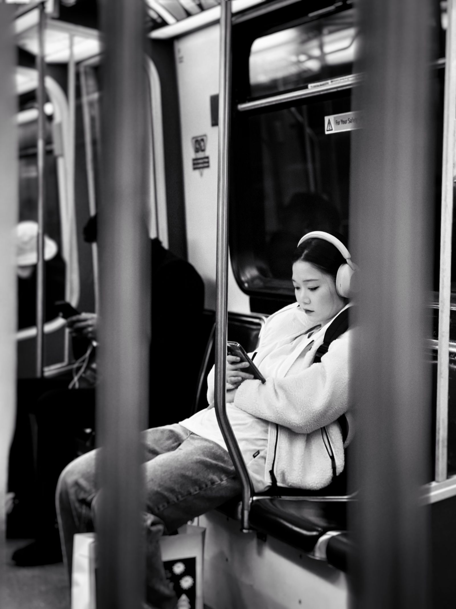 Une personne avec un casque est assise dans une rame de métro.